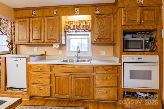 kitchen featuring a sink, white appliances, brown cabinets, and light countertops