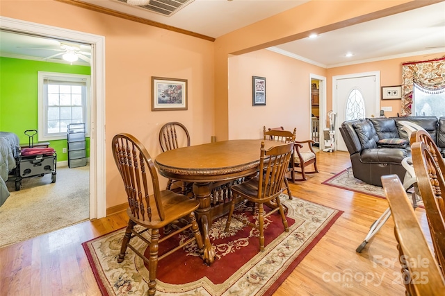 dining area with crown molding, light wood-style floors, visible vents, and baseboards