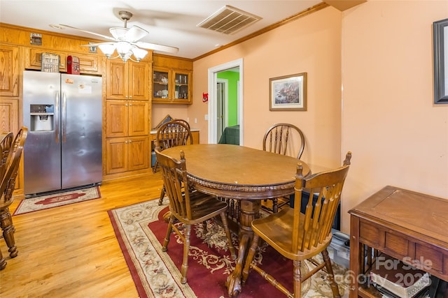 dining area featuring visible vents, ceiling fan, crown molding, and light wood-style floors