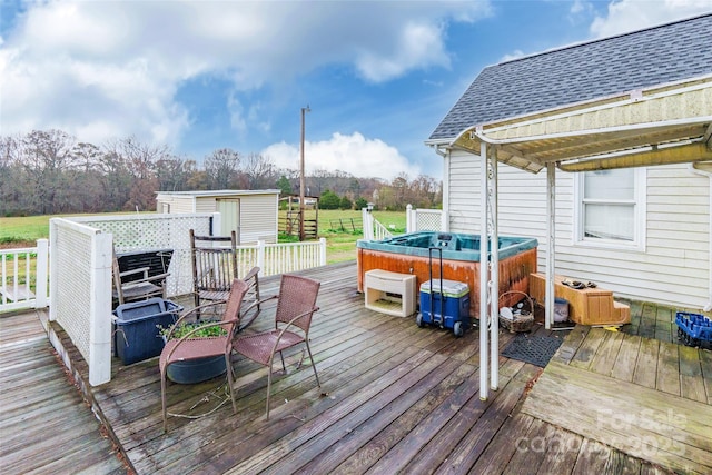 wooden deck featuring an outbuilding, a hot tub, and a storage shed