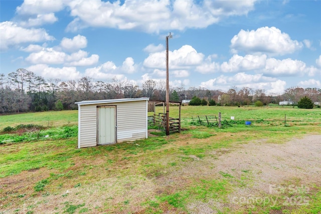 view of outbuilding featuring an outbuilding, a rural view, and fence