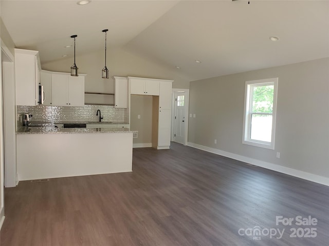 kitchen featuring light stone counters, a sink, tasteful backsplash, a peninsula, and range