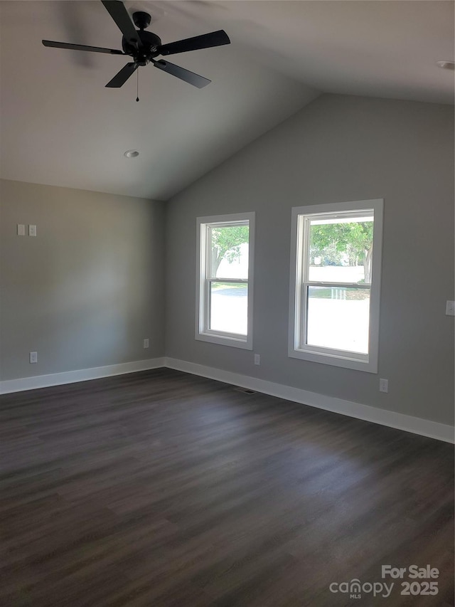 spare room featuring vaulted ceiling, plenty of natural light, dark wood-style floors, and baseboards