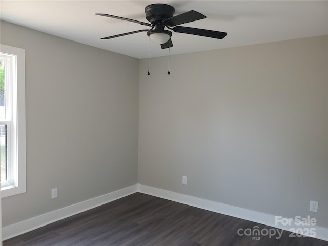 empty room featuring dark wood-style floors, a ceiling fan, and baseboards