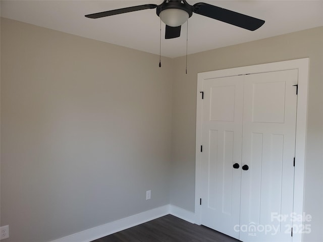 unfurnished bedroom featuring ceiling fan, a closet, baseboards, and dark wood-style floors