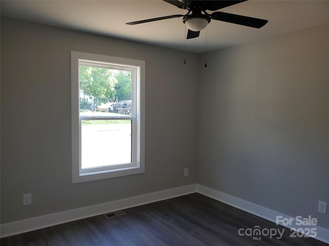 unfurnished room with visible vents, baseboards, ceiling fan, and dark wood-style flooring