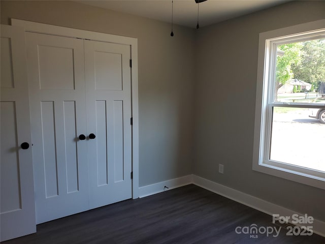 unfurnished bedroom featuring a closet, baseboards, and dark wood finished floors