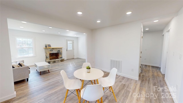 dining space featuring visible vents, recessed lighting, a fireplace, light wood finished floors, and baseboards