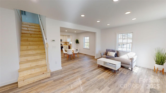 living room with light wood finished floors, visible vents, baseboards, stairway, and recessed lighting