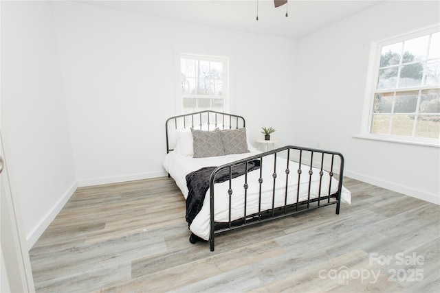 bedroom with a ceiling fan, wood finished floors, and baseboards