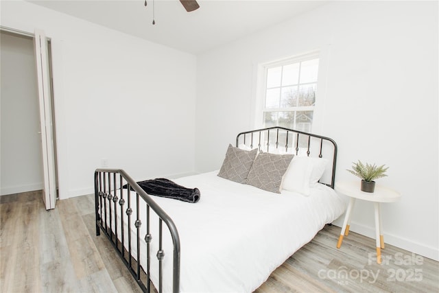 bedroom with a ceiling fan, light wood-style floors, and baseboards