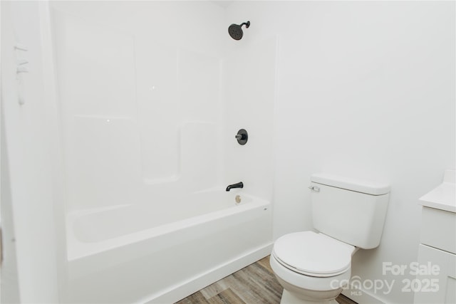 bathroom featuring toilet, shower / washtub combination, wood finished floors, and vanity