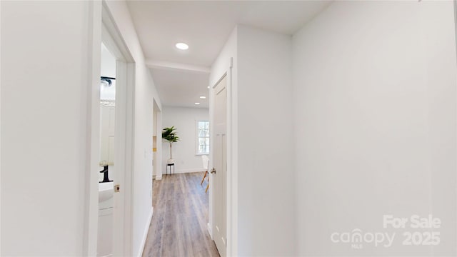 corridor featuring recessed lighting, baseboards, and light wood finished floors