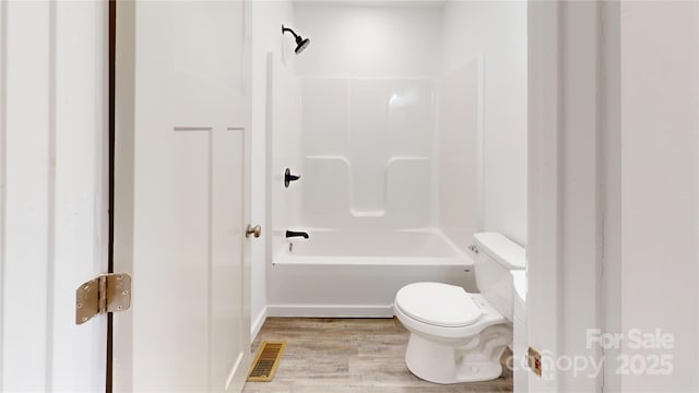 bathroom featuring visible vents, washtub / shower combination, toilet, and wood finished floors