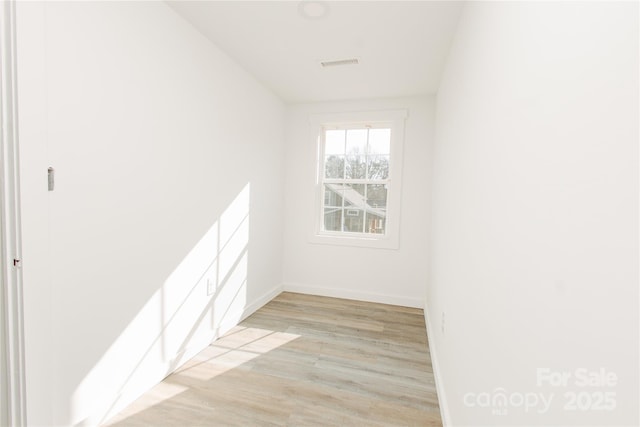 unfurnished room with baseboards, visible vents, and light wood-type flooring