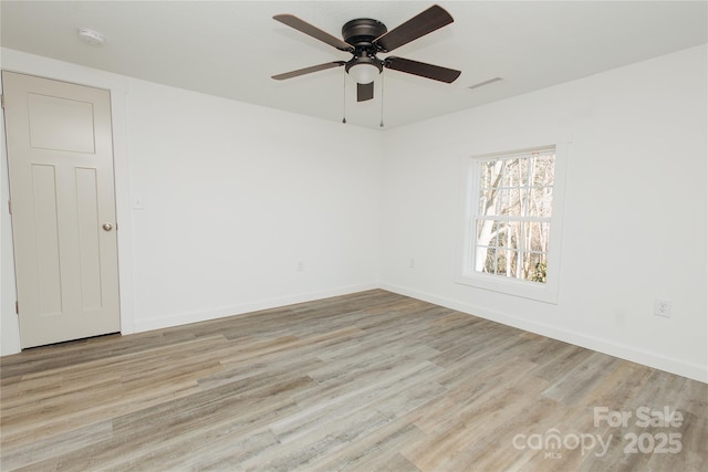 empty room with wood finished floors, visible vents, and baseboards