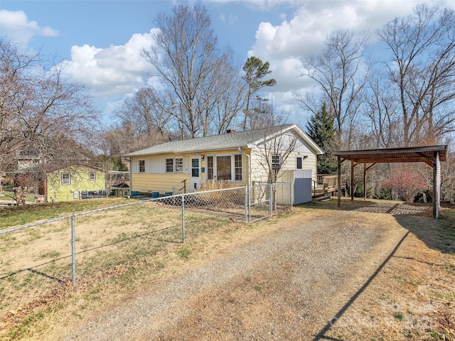 view of front of house featuring a carport, fence private yard, and dirt driveway