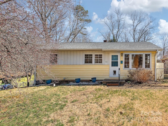 single story home featuring roof with shingles, board and batten siding, a front lawn, and fence