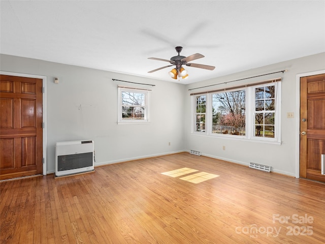 unfurnished living room featuring heating unit, visible vents, light wood-style flooring, and baseboards