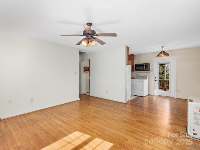 unfurnished living room with a ceiling fan, washer / clothes dryer, light wood-style floors, and baseboards