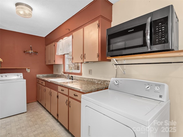 clothes washing area with washer and dryer, light floors, and a sink