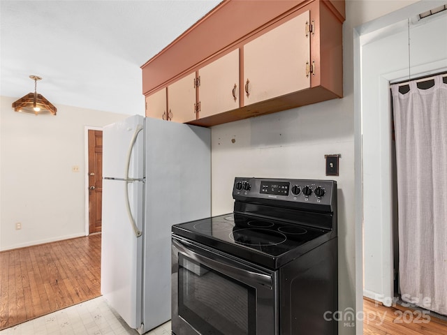 kitchen with baseboards, freestanding refrigerator, light wood-style floors, and black electric range