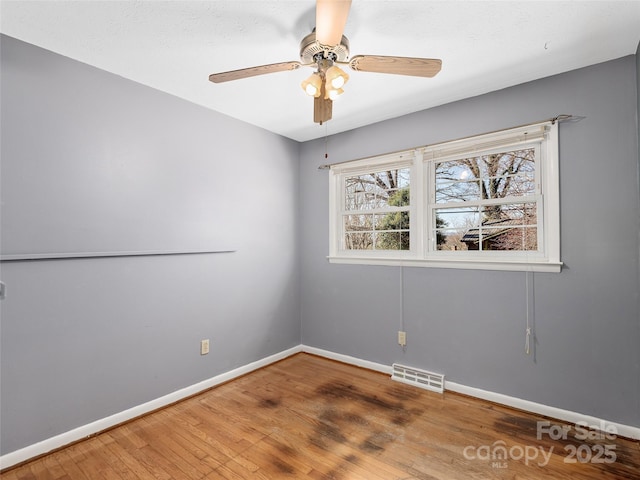 empty room with visible vents, baseboards, a ceiling fan, and hardwood / wood-style flooring