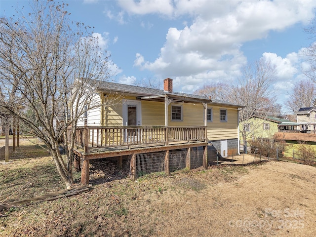 rear view of property featuring a wooden deck and a chimney