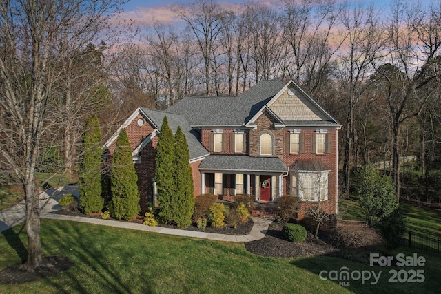 view of front of property featuring a front lawn, brick siding, and a shingled roof