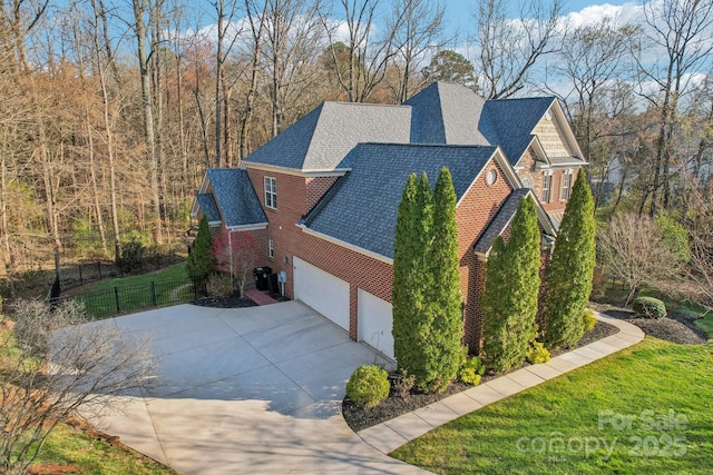 view of property exterior with fence, driveway, roof with shingles, a garage, and brick siding