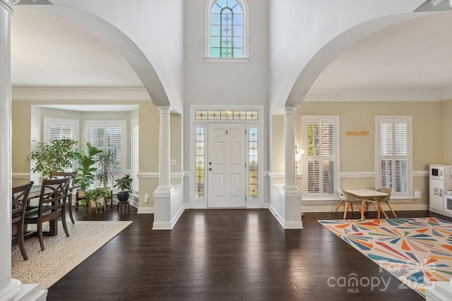 entrance foyer with baseboards, wood finished floors, ornamental molding, and ornate columns