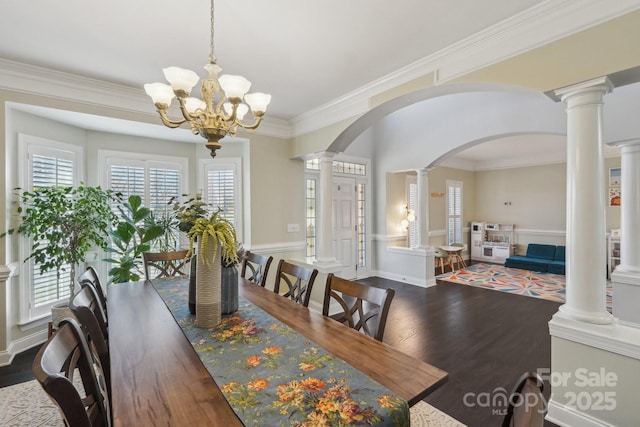 dining room with dark wood-type flooring, a healthy amount of sunlight, ornamental molding, and ornate columns