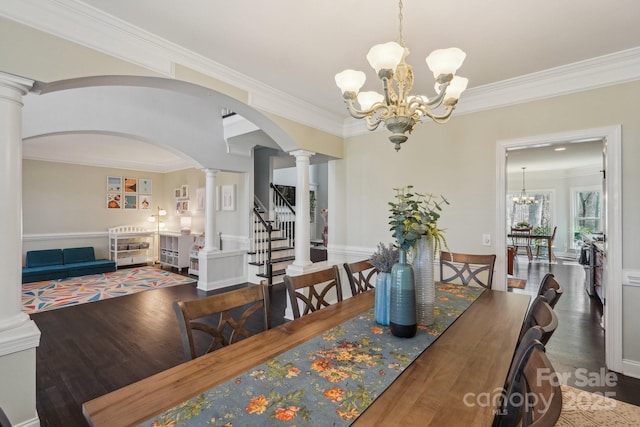 dining area with stairway, wood finished floors, an inviting chandelier, and decorative columns