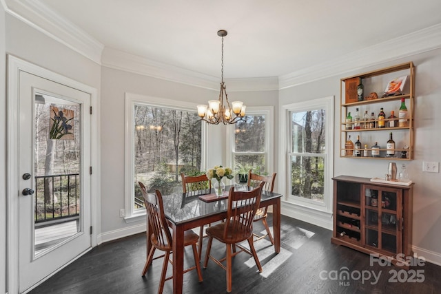 dining space with dark wood-type flooring, an inviting chandelier, and ornamental molding