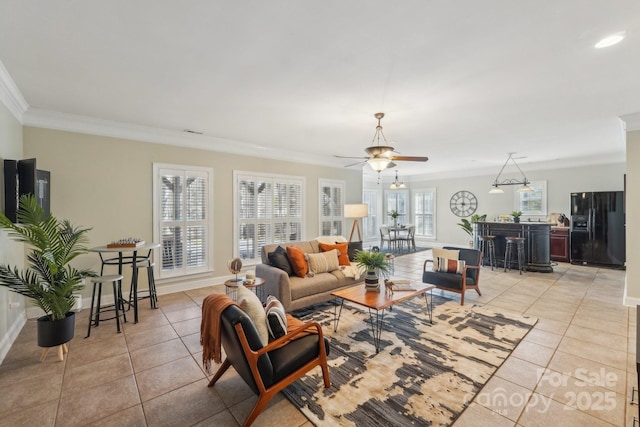 living area featuring ceiling fan, light tile patterned floors, baseboards, and ornamental molding