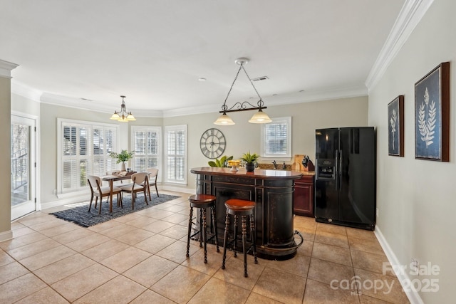 kitchen featuring light tile patterned flooring, black fridge with ice dispenser, plenty of natural light, and ornamental molding