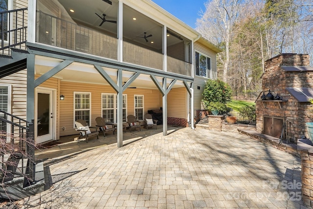 view of patio / terrace with an outdoor stone fireplace and a ceiling fan