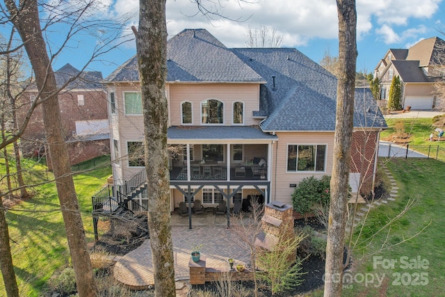 rear view of house with a patio, roof with shingles, a sunroom, stairs, and a lawn