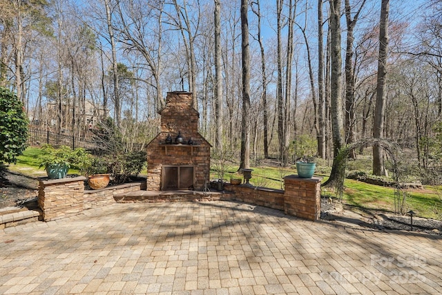 view of patio featuring fence and an outdoor stone fireplace