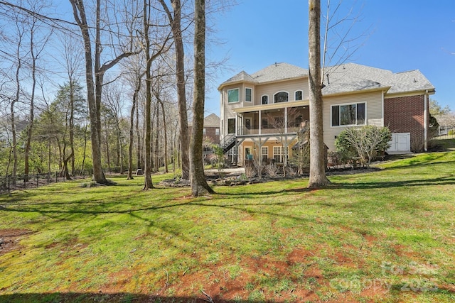 back of house with a yard, brick siding, stairs, and a sunroom