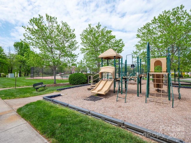 community jungle gym featuring a yard and fence