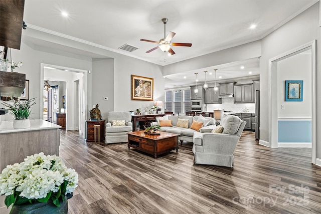 living room with visible vents, dark wood-style floors, ceiling fan, and crown molding