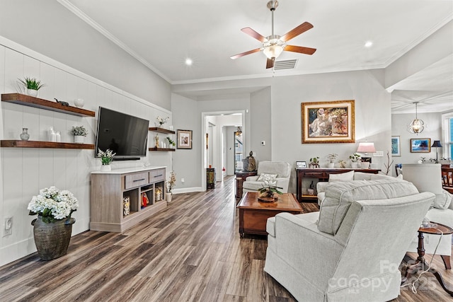 living area with a ceiling fan, visible vents, baseboards, dark wood finished floors, and crown molding