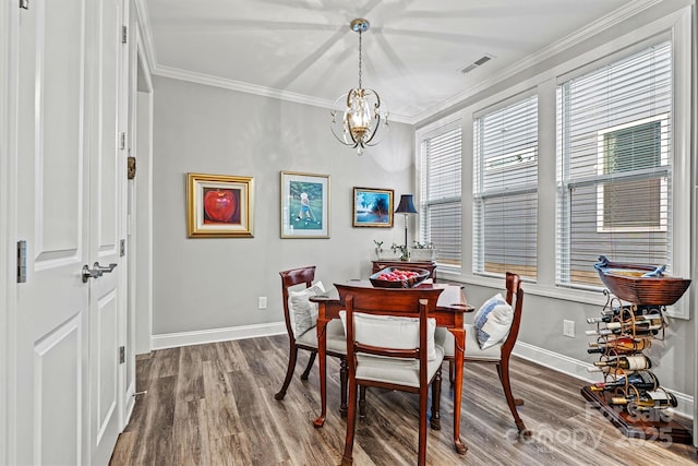 dining space with a notable chandelier, wood finished floors, visible vents, and ornamental molding