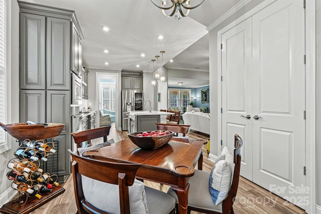 dining room with recessed lighting, light wood-style flooring, a chandelier, and crown molding