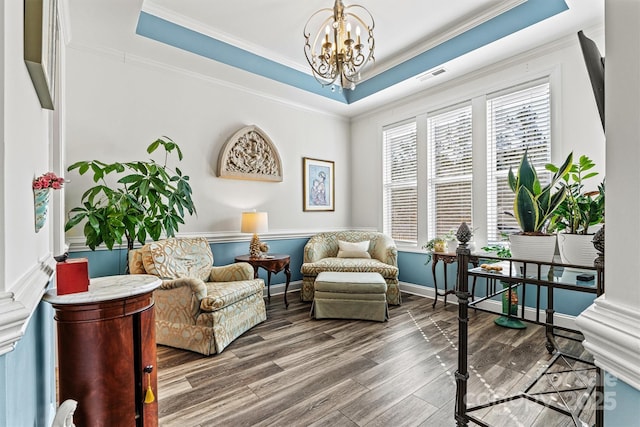 sitting room with visible vents, crown molding, a chandelier, wood finished floors, and a raised ceiling