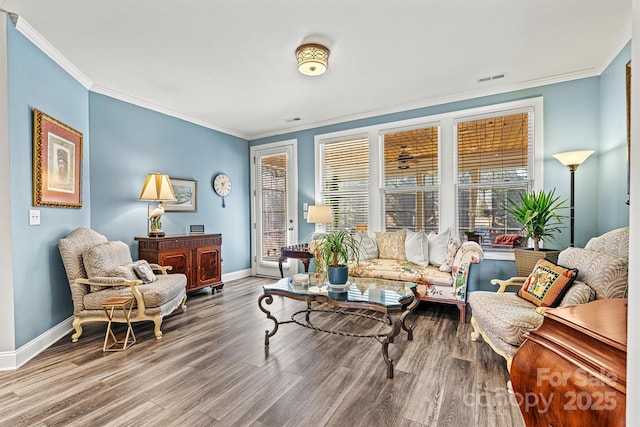 living area featuring visible vents, wood finished floors, baseboards, and ornamental molding