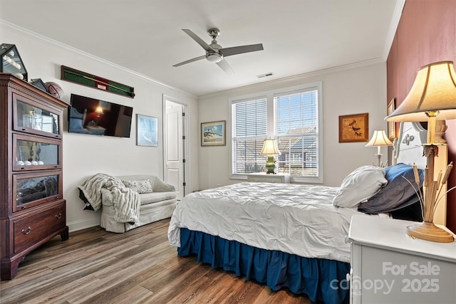 bedroom featuring ceiling fan, wood finished floors, visible vents, and ornamental molding