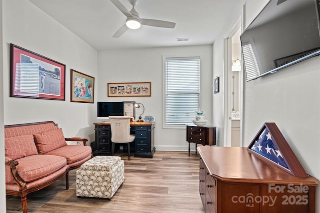 office area with visible vents, baseboards, light wood-style floors, and a ceiling fan