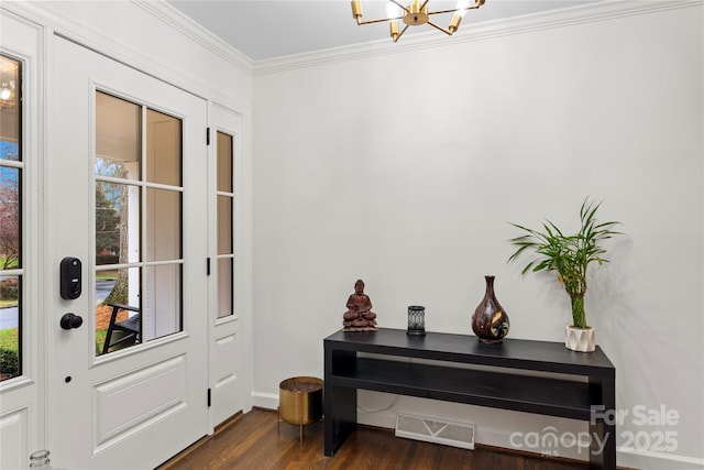 foyer with visible vents, an inviting chandelier, ornamental molding, and dark wood-style flooring